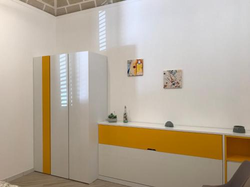 a white room with a desk and a yellow drawer at LA DIMORA SICILIANA APPARTAMENTI in Trapani