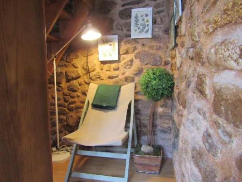 a chair in a room with a stone wall at Casa do Forno in Almeida