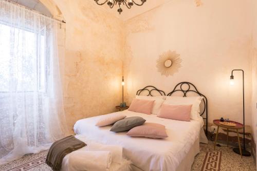 um quarto com uma cama com lençóis brancos e uma janela em Le Maria Country Luxury Villa em Ragusa