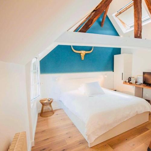 ein Schlafzimmer mit einem weißen Bett und einer blauen Wand in der Unterkunft La Maison des Arts, Le Six in Honfleur