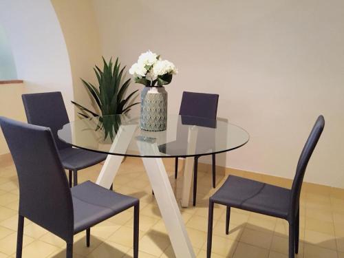 een glazen tafel met stoelen en een vaas met bloemen erop bij Gstar Flat in Piano di Sorrento