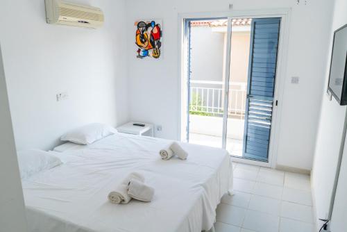 a white bedroom with a bed with towels on it at Helios Cottages in Paphos City