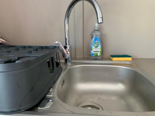 - un lavabo avec une bouteille de détergent à côté dans l'établissement Chalet 3 chambres en Bois dans les landes n37, à Tosse