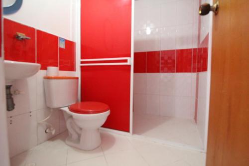 y baño rojo con aseo y ducha. en HOTEL PORTÓN ESTADIO, en Medellín