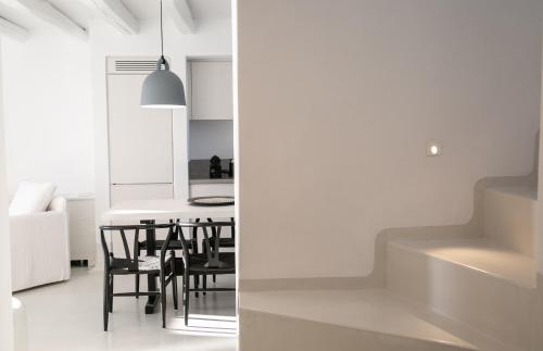 una cucina e una sala da pranzo con pareti bianche e sedie nere di Philosophia Luxury Villa a Megalochori