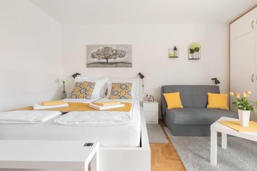 a white living room with a bed and a couch at Studio apartman Comodo in Zagreb