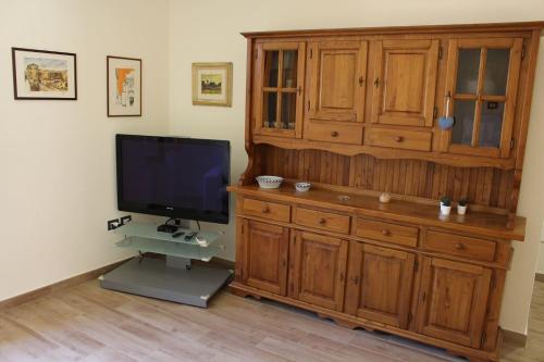 a living room with a tv and a large wooden cabinet at Daniele Guest Apartment in Pistoia