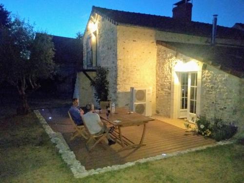 twee mensen die 's nachts aan een tafel op een terras zitten bij La Chaumerie in Chenevelles