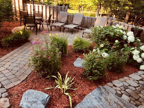 a patio with chairs and flowers in a yard at Relais St-Denis in Saint-Sauveur-des-Monts