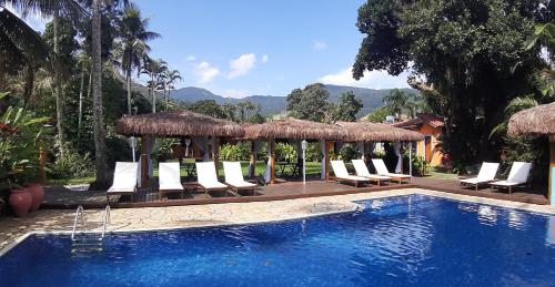 a swimming pool with lounge chairs and a resort at Pousada Canoa Caiçara Ilhabela in Ilhabela