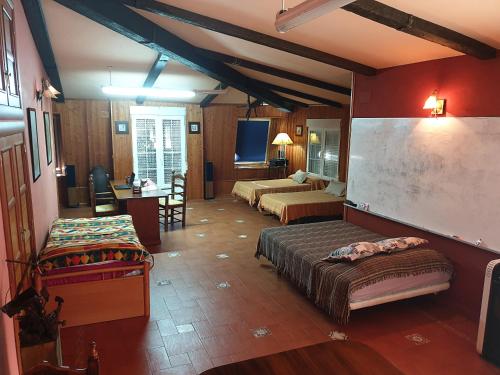 ラ・ローダにあるAmplia y luminosa buhardilla & total independenciaのベッド2台、デスク、テレビが備わる客室です。