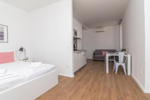 a white living room with a table and a couch at Apartments and Rooms Jospino in Mali Lošinj
