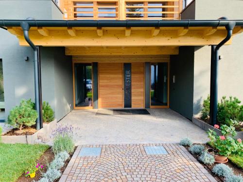 a house with a wooden door and a patio at Affittacamere Casa Ester in Baselga di Pinè