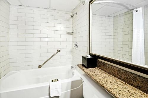 a white bathroom with a tub and a mirror at Best Western Plus Banff International Lodge in Banff