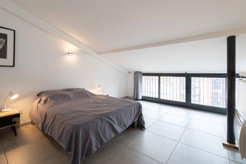 een slaapkamer met een bed, een bureau en ramen bij 303 - Appartement Duplex Moderne - Jeanne d'Arc, Toulouse in Toulouse