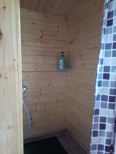 eine hölzerne Dusche mit einer Flasche auf einem Regal in der Unterkunft E.A.MINIKAMP in Lelle
