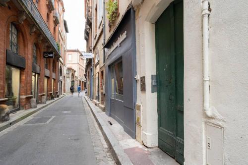 uma rua vazia com uma porta verde num edifício em Appartement 1 - tout équipé et fonctionnel - Carmes, Toulouse em Toulouse