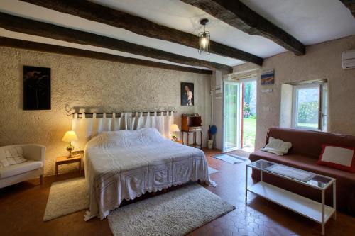 een slaapkamer met een bed en een bank bij Chambres d'hôtes Noailles in Puisseguin