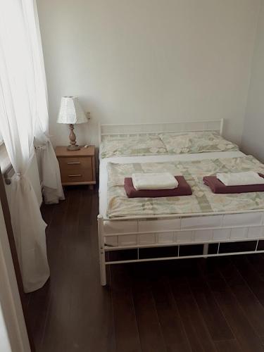 ein Schlafzimmer mit einem Bett und einem Tisch mit einer Lampe in der Unterkunft Kwatera Jolanta in Lyck