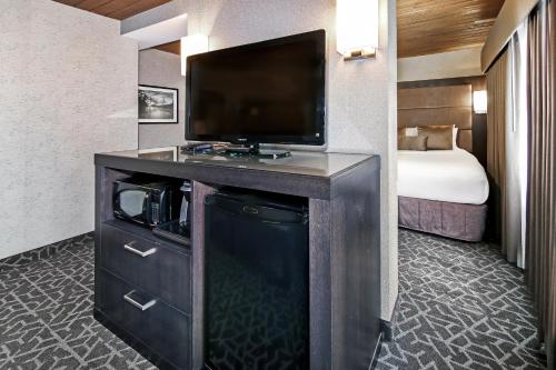 a hotel room with a flat screen tv and a bed at Best Western Plus Banff International Lodge in Banff