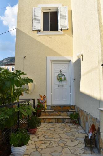 a house with a white door and a stone walkway at J&B Rooms Dhermi in Dhërmi