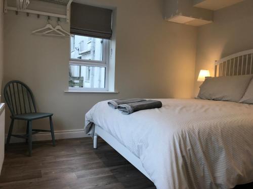 a bedroom with a bed and a chair and a window at Bush House Accommodation - The Courthouse Apartment in Bushmills