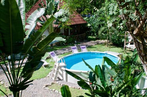 a swimming pool with two chairs and a table at Naturalmente Boutique Bungalows y Cocina Mediterránea in Las Lajas