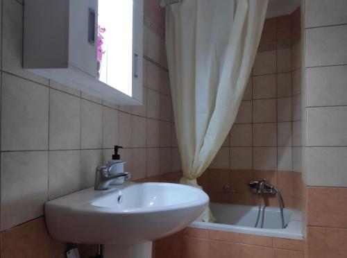 een badkamer met een wastafel en een bad met een raam bij Old Town Venetian Studio by CorfuEscapes in Corfu-stad