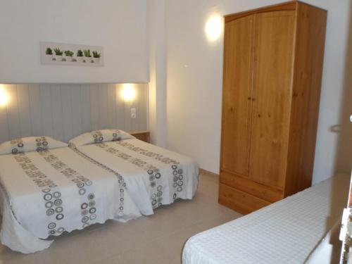 バレンシアにあるHostal La Barracaのベッドルーム1室(ベッド2台、木製キャビネット付)