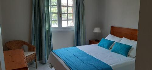 um quarto com uma cama com almofadas azuis e uma janela em CASA JABLILLO em Costa Teguise
