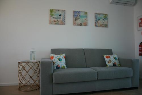 a blue couch in a living room with pictures on the wall at Recantus Comporta in Comporta