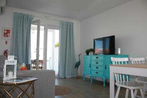 sala de estar con cómoda azul y TV en Recantus Comporta, en Comporta