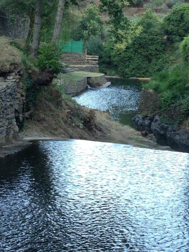 a river with a bridge in the middle of it at Casa Rural Valle del Arrago in Robledillo de Gata