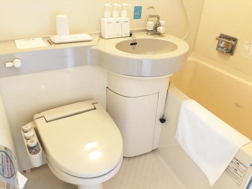 y baño con aseo blanco y lavamanos. en Ace Inn Matsusaka, en Matsusaka