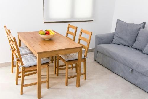 a wooden table with a bowl of fruit on it next to a couch at Ellie Apartments Stalida in Stalida