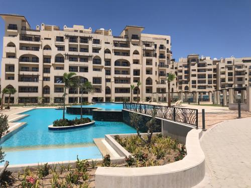 un grand bâtiment avec une piscine en face d'un bâtiment dans l'établissement AlDau Heights Apartments, à Hurghada