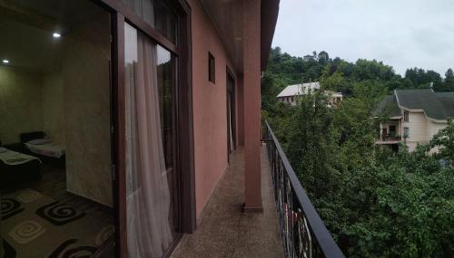 a balcony of a pink building with a view of a house at Batumi Homestay at Tamar Mephe Avenue in Makhinjauri