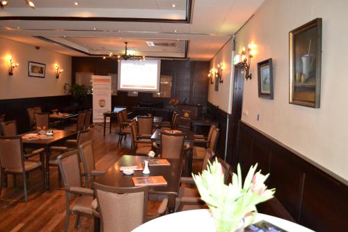 a restaurant with tables and chairs and a projection screen at Hotel Het Wapen van Drenthe in Roden