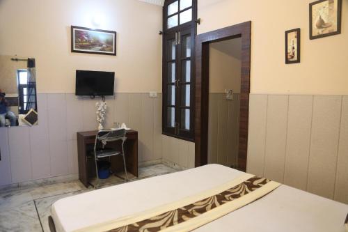 a room with a bed and a tv and a door at Time Square Guest House in Jalandhar