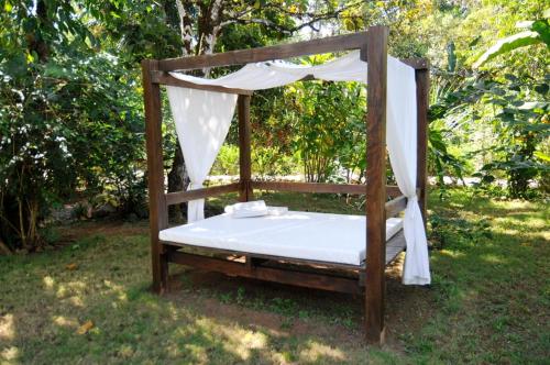 a bed with a canopy in the grass at Naturalmente Boutique Bungalows y Cocina Mediterránea in Las Lajas