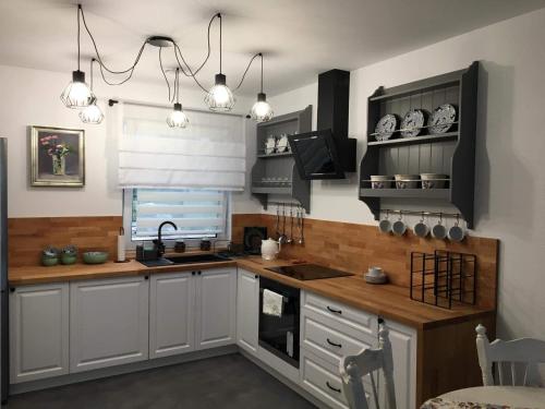 a kitchen with white cabinets and wooden counter tops at Apartament Roztocze in Zamość