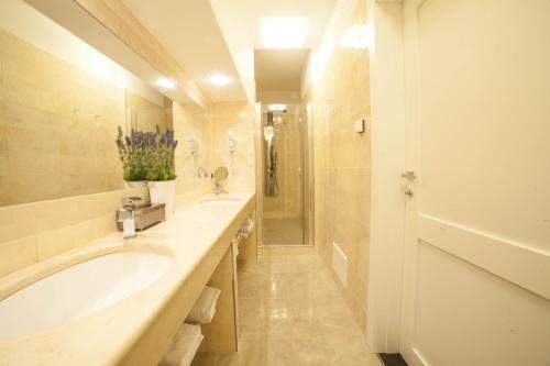 ein Badezimmer mit zwei Waschbecken, einer Badewanne und einer Dusche in der Unterkunft Roccamonfina Palace Hotel in Roccamonfina