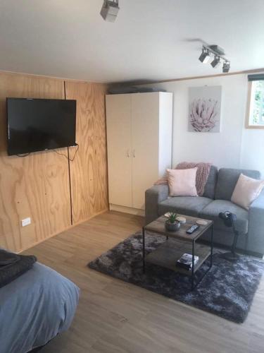 a living room with a couch and a flat screen tv at Studio with water views in Omokoroa