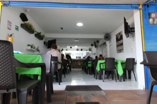 uma sala de jantar com mesas e cadeiras verdes em HOTEL MANAGER OBELISK em Medellín