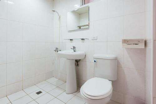 a white bathroom with a toilet and a sink at Fengjia Love I Hostel in Taichung