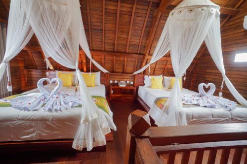 2 camas en una habitación con cortinas blancas en Daphila Cottage en Nusa Penida