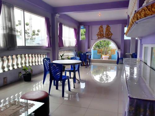 Trivadoh Syariah Hotel في Padangpanjang: غرفة طعام بجدران أرجوانية وطاولة وكراسي
