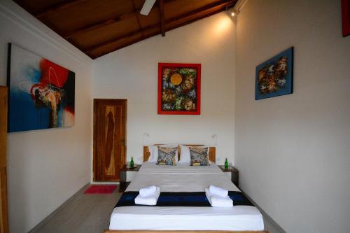 1 dormitorio con 2 camas y pinturas en la pared en World BnB, en Labuan Bajo