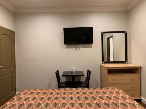 a bedroom with a bed and a table and a mirror at El Rey Inn - LAX in Gardena