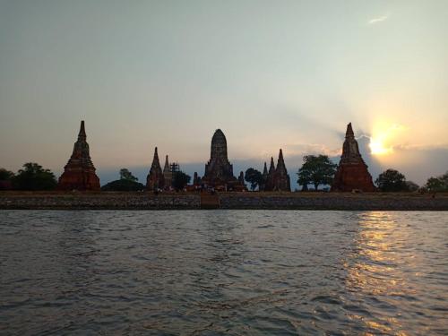 a view of a temple from the water at sunset at Siri Guesthouse in Phra Nakhon Si Ayutthaya